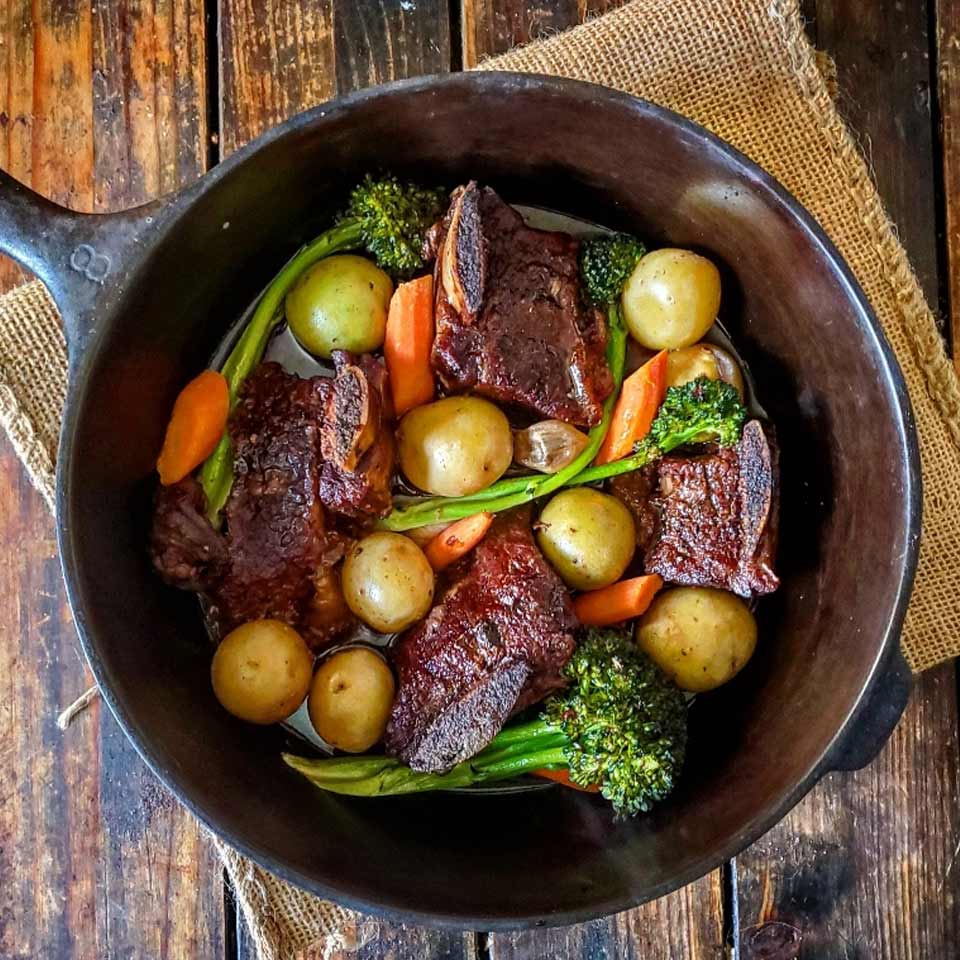 Braised Short Ribs Dinner Recipe with falll vegetables in a cast iron skillet